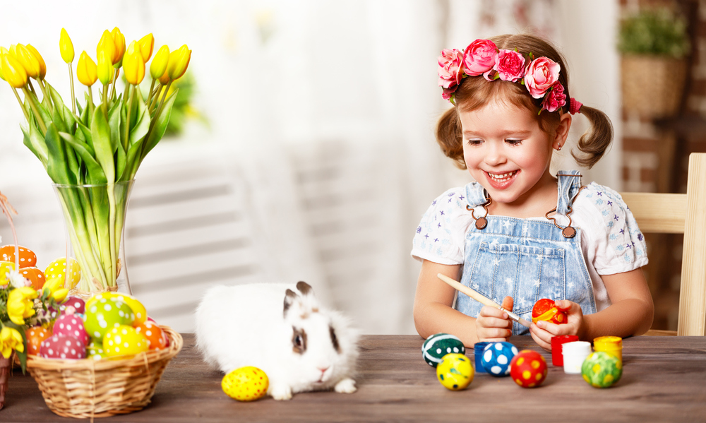 Happy easter! happy baby girl paints eggs for holiday  at home